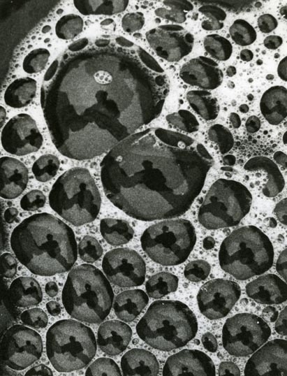 Bubblor bildas på vattenytan, i trakterna runt Knyssla den 1 maj 1959. I bubblorna syns speglingar av fotografen.