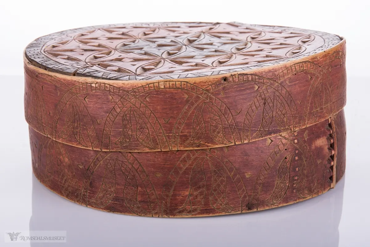 Eit slag seksbladrosemønster på lokk. Bueformede skaverte border på trosken.