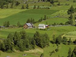 Nyhus. Kulturlandskap. Hvit bygning,rødbrunt uthus. Hage. Dy