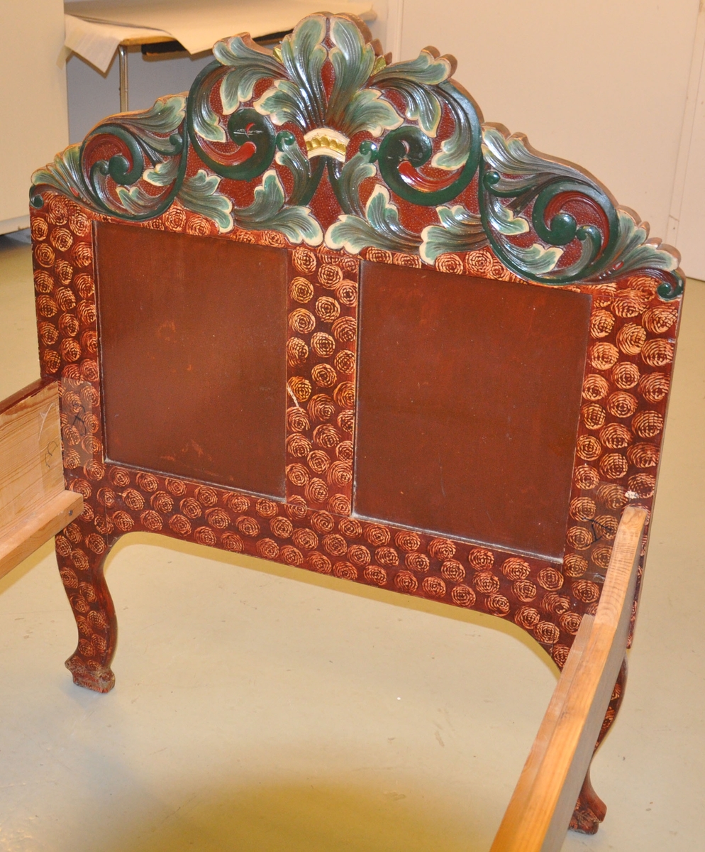 Seng med to sengegavler og to sidevanger. Den ene sidevangen er skåret ned på et lavere nivå. Ryggavlen er høyere enn fotgavlen. De har begge to fyllinger og krone prydet med akantusskurd. Fotgavlens fyllinger har skårne akantusrosetter på utsiden. Svungne bein. Treskurden er polykrom, mens senga er malt lys elgfenbeinsfarget med brun maling over, der en form for stempel har vært brukt for å fjerne deler av overmalingen, slik at et konglelignende mønster framtrer.