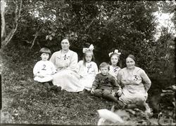 Gruppebilde. Kvinner og barn sitter ute i naturen.