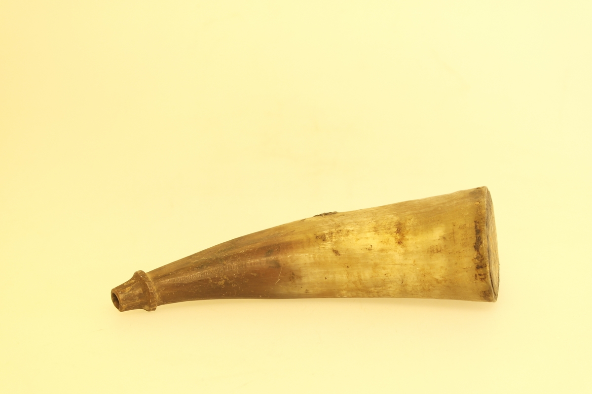 Krutthorn, skåret, pusset. Den brede enden er trukket av en treplate i bjørk. I denne er det skåret initialer og et årstall. Brukt til oppbevaring av krutt.