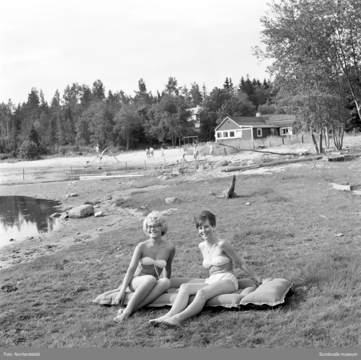 Två unga kvinnor vid en badvik med strand och klippor i Söråker.