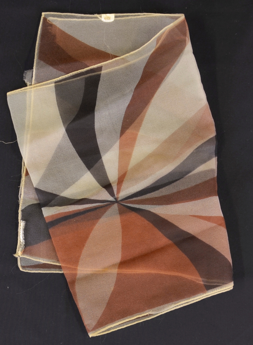 Gjennomskineleg sjal med dekor med brune, svarte og kvite stripar stråalnde ut ifrå eit senter. Rektangulær form.
