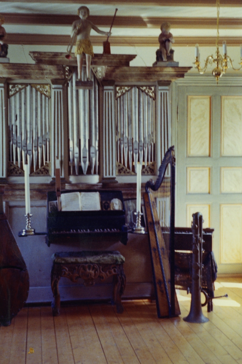 Bilde av Vollanorglet i orgelrommet. Det står en cecilium og en harpe ved siden av orgelet.