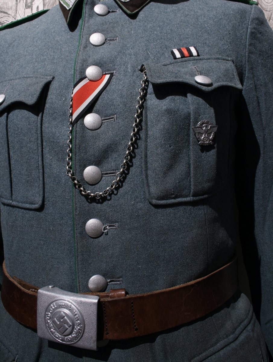 Full uniform med støvler. På brystet har den en pins (Politiets dag 1942), en bånd (Minne-/deltakermedalje 1914-1918) og EK. 2. klasse bånd. Den har også fløyte i brystlommen. 

Skulderdistinksjoner til en oberwachtmeister

I lommen var det stoff lapper og sytråd med nål. 

På beltet har den pistolhylster med Walther PP magasin.