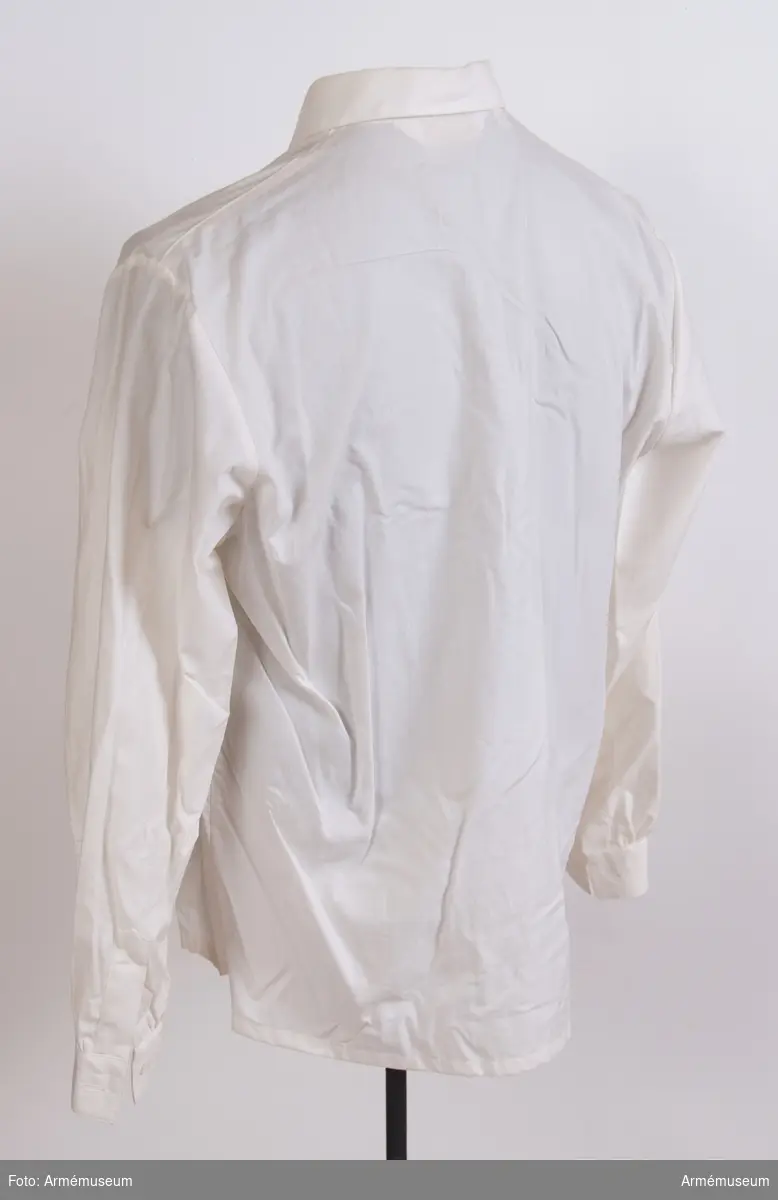 Vit skjorta i bomullstyg med plastknappar.
Etikett i nacken: "Creation Eaton, M 38, made in Sweden, 100 % cotton, tvättråd".