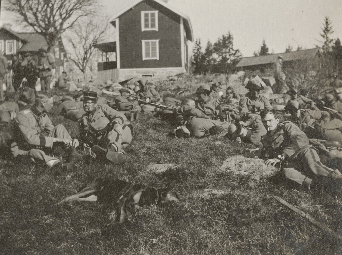 Soldater från Göta livgarde I 2 har paus på gräsmattan framför ett trähus.