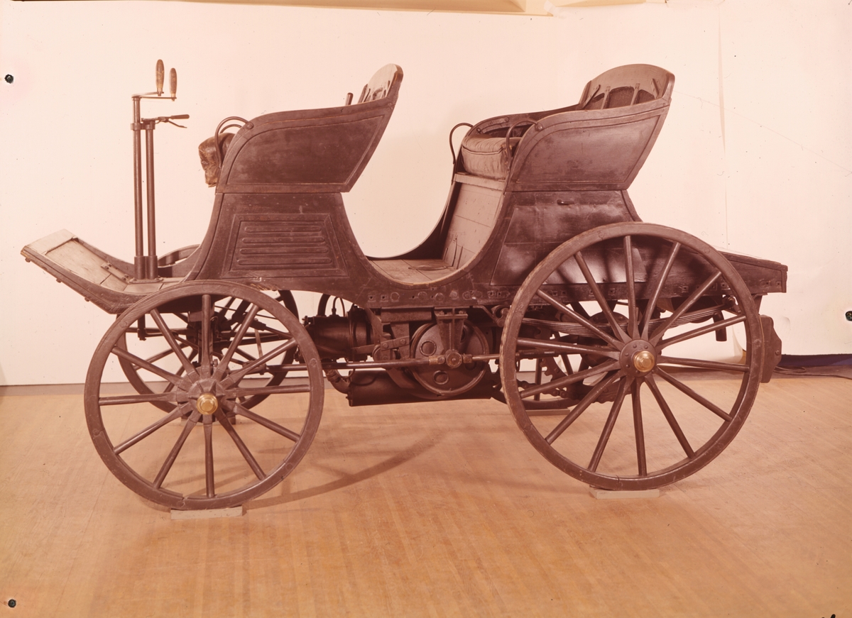 Åkvagn för 4 personer. Den första förbränningsmotordrivna bilen som byggts i Sverige. I detta sista utförande från 1901 ligger en fotogenmotor under vagnsgolvet, vilken startas med vev. Reglage på en styrkolonn under styret, spak för i- och urkoppling av motorn samt handbromsspak på höger sida. Vagnskorg av trä och hjul byggda av C A Carlsson & Söner i Stockholm. Korgen byggd speciellt för bilen och bakhjulen är kraftigt utförda för att tåla att användas som drivhjul.  Tvåcylindrig vattenkyld fotogenmotor. Cirka 5 hästkrafter. Växlar saknas, motorn är omkastningsbar för gång fram eller back. Glödrörständning, värmdes med blåslampa. Totalvikt cirka 600 kg, motorn 200 kg.
Tillbehör: Två medar för körning i snö som kan monteras istället för framhjulen.