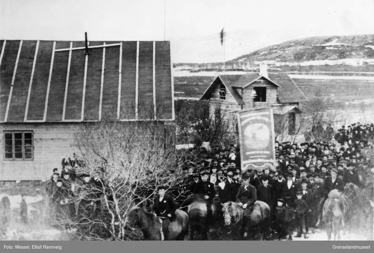 Første 1. mai-tog i Kirkenes, 1907. Fanen til Arbeiderforeningen Nordens Klippe midt i bildet. Bak murmester Soots hus.