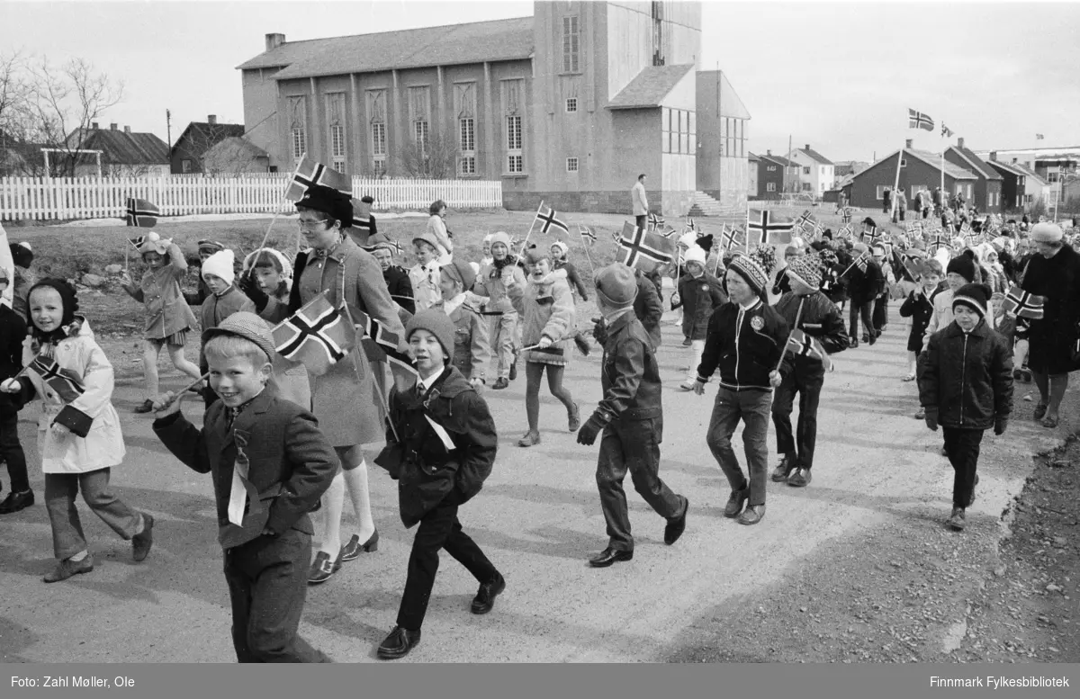 Vadsø, 17.mai 1970. Korpset spiller i gatene. Vadsø kirke i bakgrunnen.