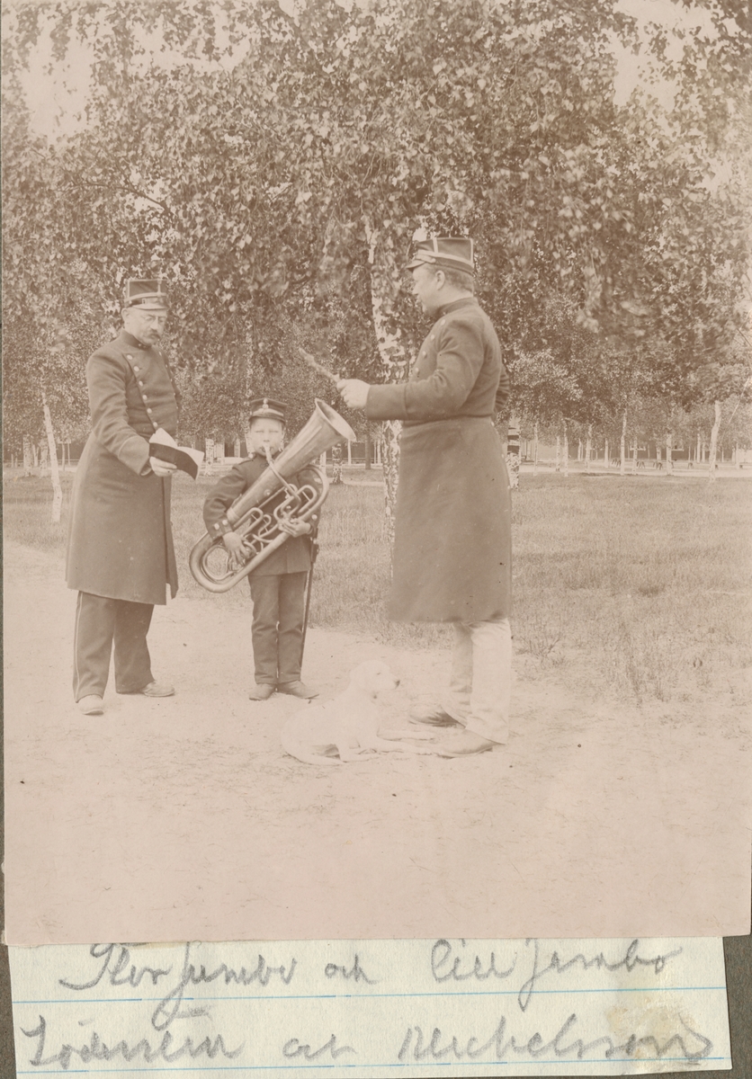 En officerare dirigerar ett barn som spelar bastuba, en annan officerare håller upp ett nothäfte.