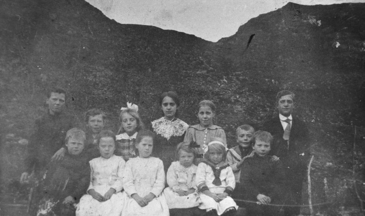 En barnegruppe med tretten barn stillt opp i finere klær.