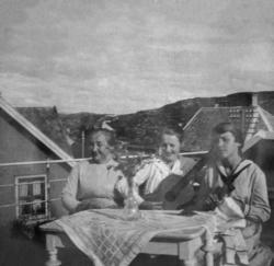 Foto av tre kvinner på verandaen, hvor kvinnen i midten spil