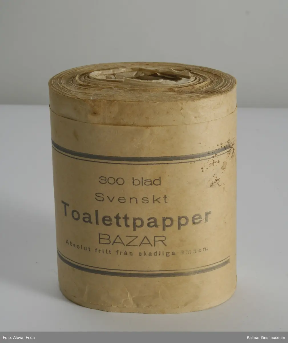 KLM 44780, Toalettpapper, av papper. En rulle toalettpapper. På omslagspappret texten: 300 blad Svenskt Toalettpapper Bazar Absolut fritt från skadliga ämnen.