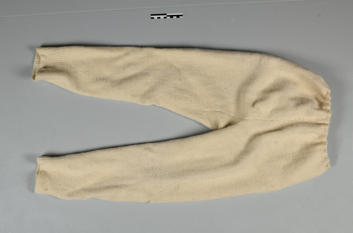 Underbukse - ull, strikket - rettstrikning, hvit, gylfhull med 1 knapp, strikk  i linning, kile i skrittet, venstre kne er stoppet. 