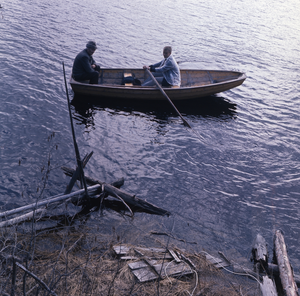 Två män, varav den till vänster är Albert Viksten, är ute i en roddbåt.