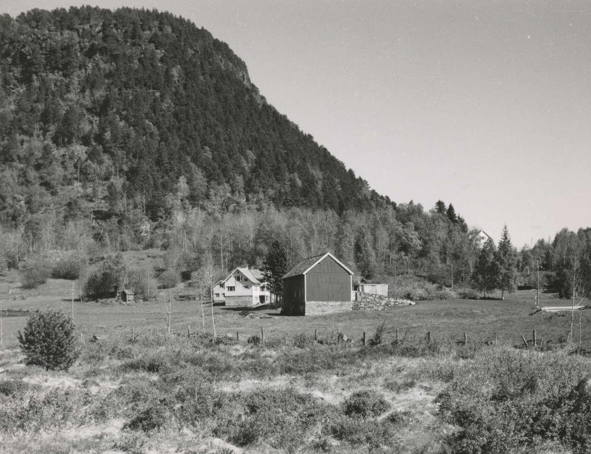 Prospektfotografi av et gårdstun på Aksla kallt Hølå. I bakgrunnen viser fjellet Akslanakken.