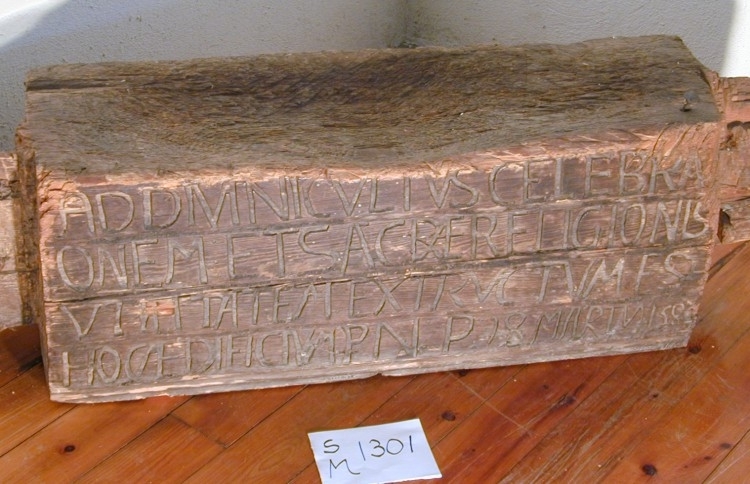 Fra protokollen:
Tømmerstok, rimeligvis fra en Bindingsværks døraapning af en ældre Kirke i Solum, nedrevet omtrent 1760, med følgende, i ophøiede Bokstaver, latinske indskrift: "ad divini cultus celebrationem et sacræ religionis utilitatam exstructum est hoc ædifiicium P. N. P. 18 marty 1580". Stokken er engang benyttet til huggeblok.

Tekst på skilt i gammel utstilling:
Bjelke fra Solum kirke
Stokken er sannsynligvis fra en bindingsverks døråpning. Den latinske teksten betyr oversatt: "Til Gudsdyrkelsens høytideligholdelse og den hellige religions nytte er denne bygning reist d. 18. mars 1580." Bygningen er sannsynligvis en påbygning av et kor til kirkeskipet på Soleimar kirke, som var viet døperen Johannes. Det var en stavkirke fra 1200-tallet. Den forfalt mer og mer og ble revet i 1760-årene.