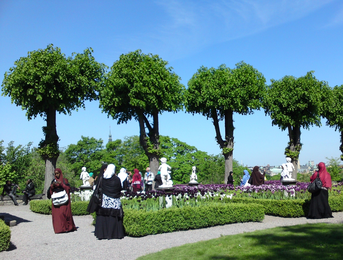 En grupp Skansengäster strövar omkring i Rosenträdgården.