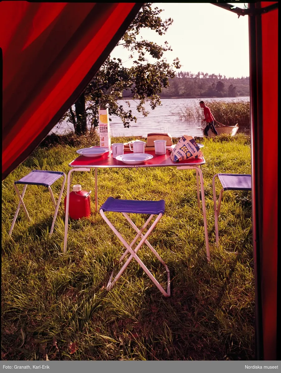Camping, frukostbord sett inifrån tältet med utsikt över en sjö.
