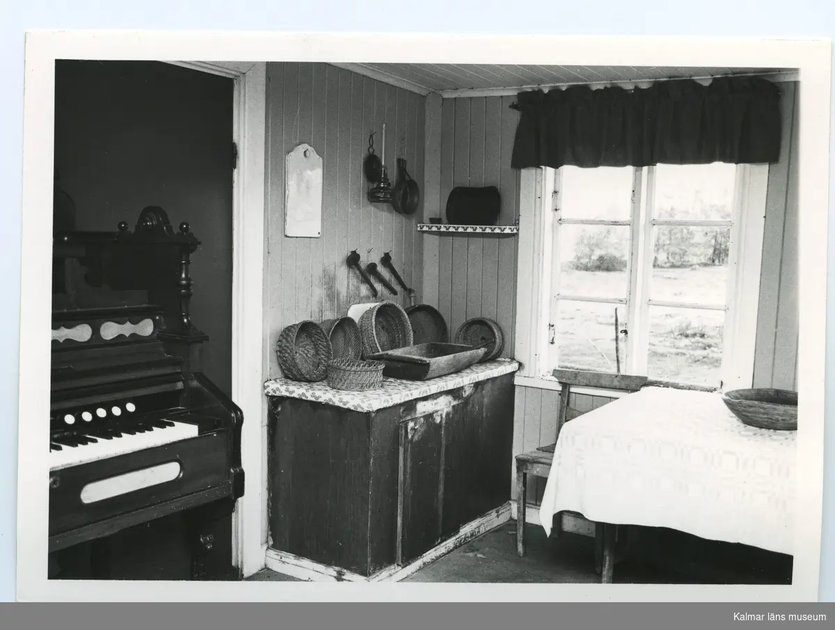 Köksinteriör, med en orgel placerad i dörröppningen till vänster i bild.