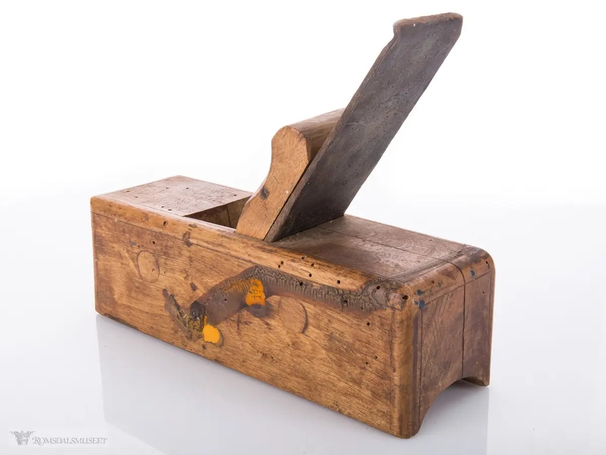 Liten rektangulær høvel med jern og kile. Konkavt u- formet spor i sålen.