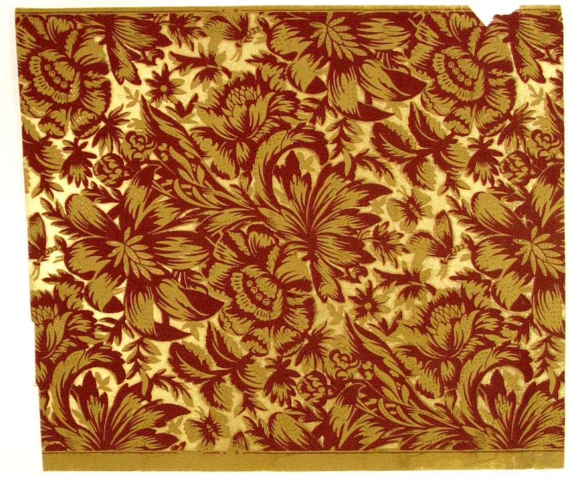 Ett livligt ytfyllande blommönster i senapsgult och brunt på en guldbelagd bakgrund.