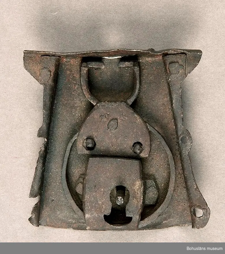 Ur handskrivna katalogen 1957-1958:
Lås, def.
Mått: 8,5 x 8,3 x 3,2 cm; av järn; kistlås, den del, som brukar sitta i locket saknas, liksom nyckel. Rostigt.