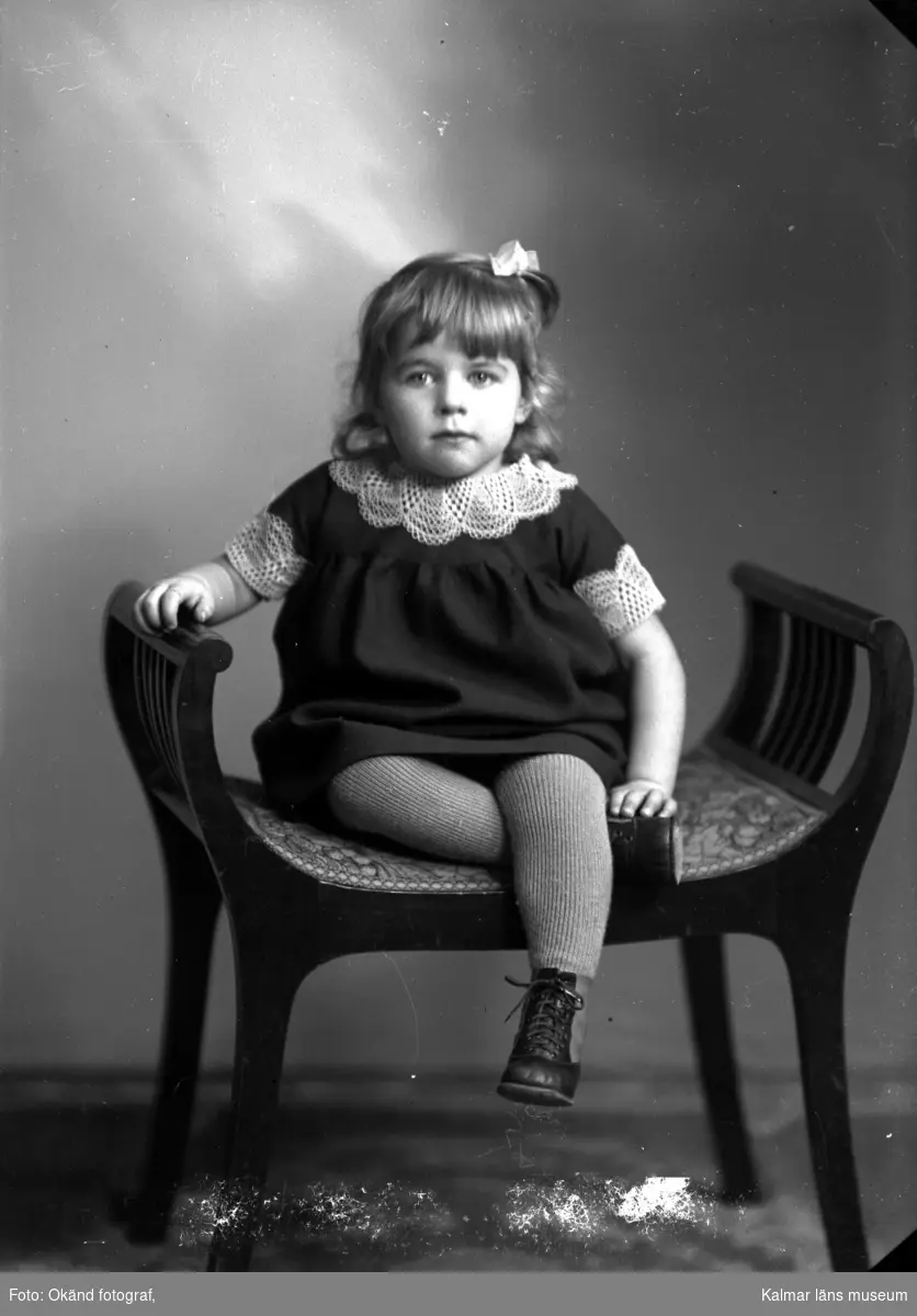Porträtt på en flicka, sittande på en pall.