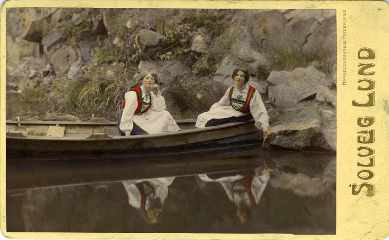 Kolorert fotografi av to kvinner med drakt i pram. 1908. (Foto/Photo)