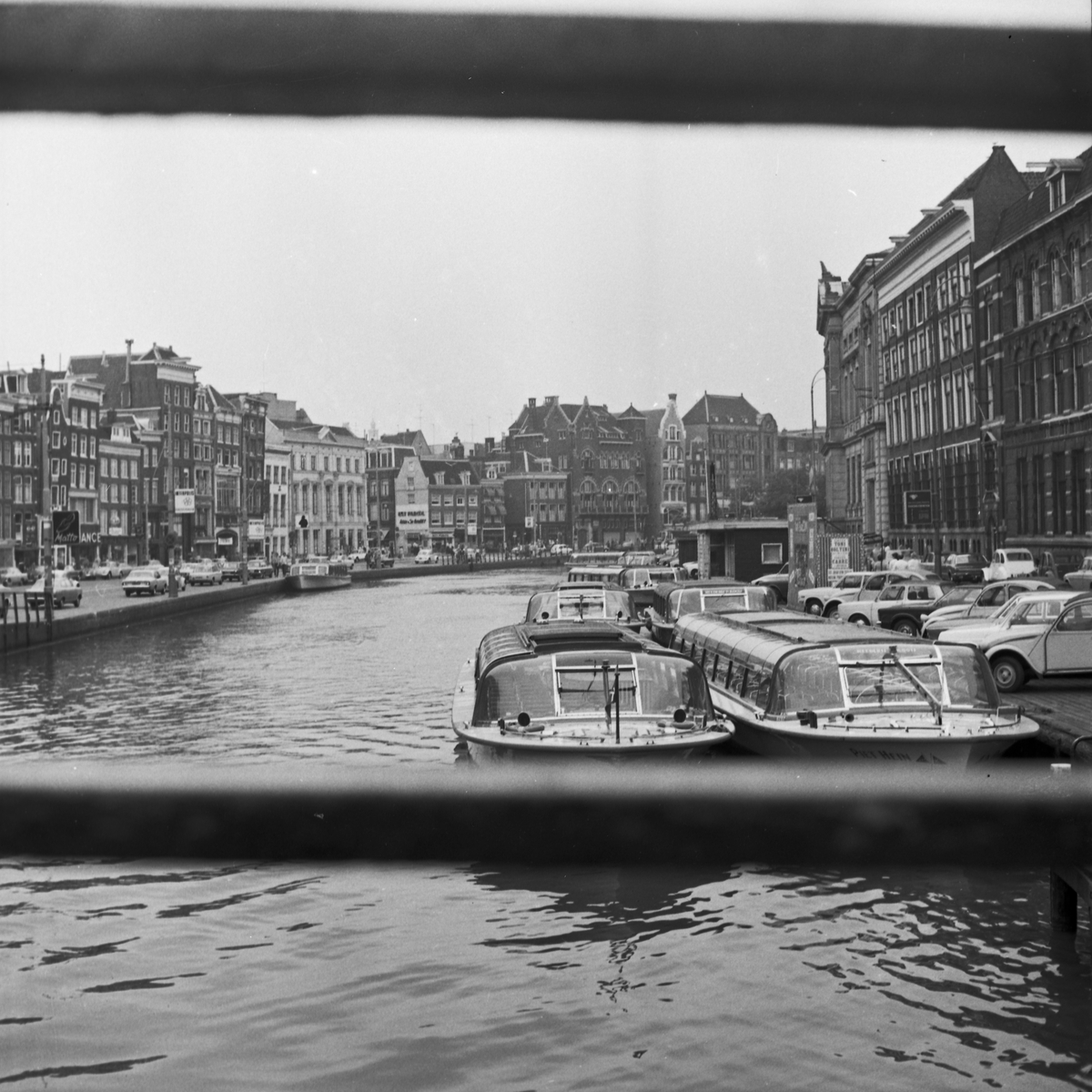 Sentrumsgater og kanaler i Amsterdam. Kanalbåter side om side med biler.