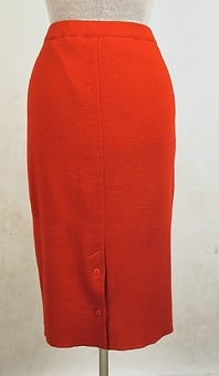 Röd maskinstickad kjol av ullgarn med tillhörande kofta (106259:1).
Slits med två knappar mitt bak. Resår i midjans linning.
Har tidigare tillhört dottern Elisabeth (givaren)