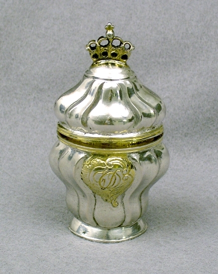 Enl liggare:
Svampdosa af silfver i form af en flaska med gängkant lock försett med en förgylld krona. På framsidan ingr. Â¨G O D.Â¨