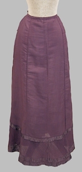 Rödaktigt blå (violett) kjol sydd av tuskaftsväd halvyllekvalité. Modellen består av fem kilformade våder av olika storlek. Nedtill är kjolen avslutad med en plisserad kant. Dragsko längs midjan baktill. Sprund mitt bak. Sidenband pryder underkjolen nedtill. Underkjolen är maskinsydd.


Neg.nr: 
Sakord: UNDERKJOL
Tillverkningstid: 1890-1920
Material: Ull bomull silke
Teknik: Vävt sytt plisserat
Mått: L=990
Vikt: