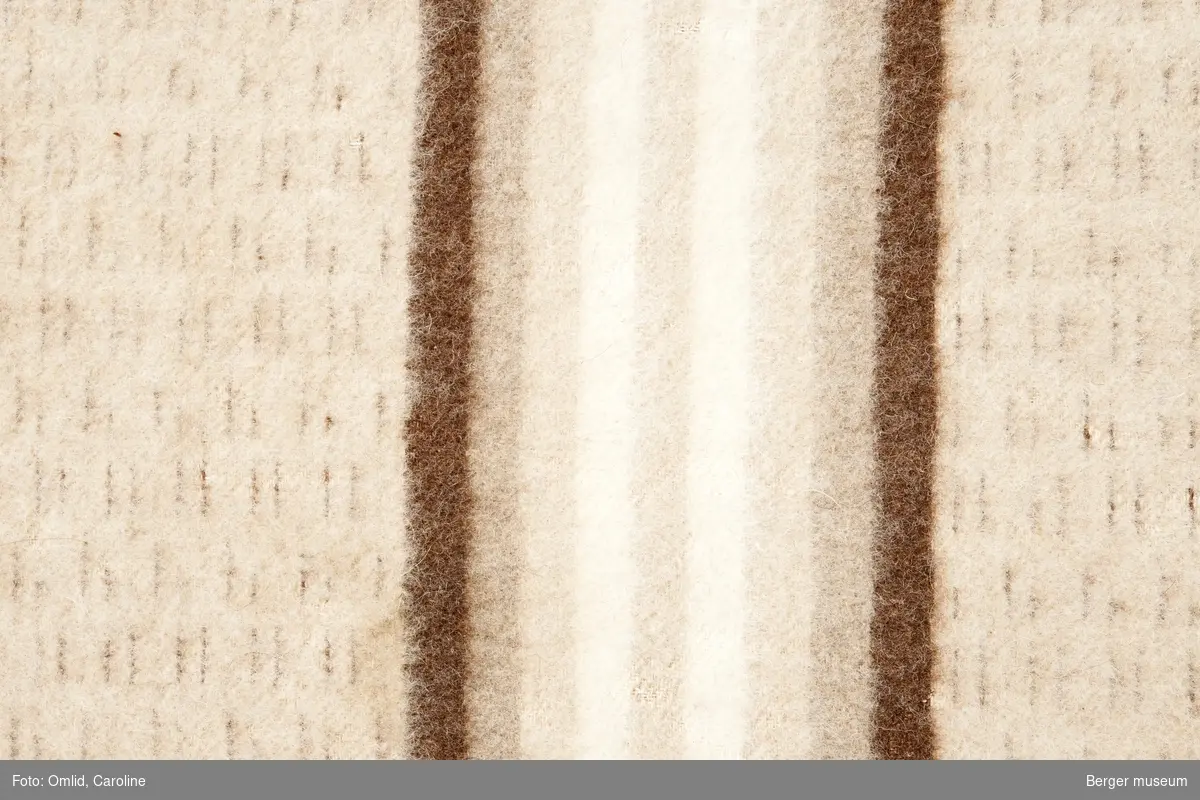Teppe med bomullsrenning med enkelte innslag av mørkebrune tråder. Bord av mørkebrunt, mellom- og lysebrunt, offwhite i striper.
