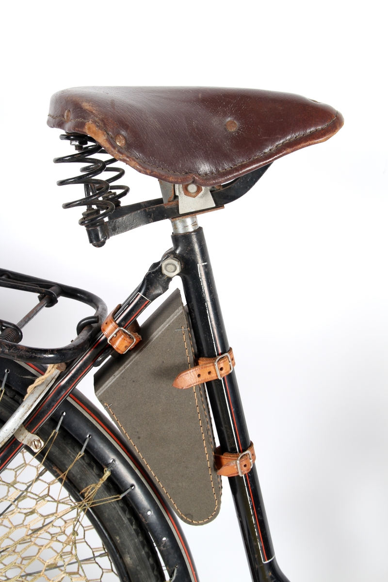 Svartlakkert damesykkel med taske til verktøy under setet og kjolenett bak. Torpedo frinav med innebygd trommelbrems.