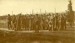 Gjeng på 20 - 30 fløtere oppstilt til fotografering. En eldr