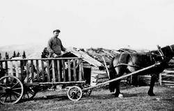 Hest og vogn, person, bygning.