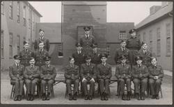 Gruppebilde av flypersonell. Bygninger i bakgrunnen.