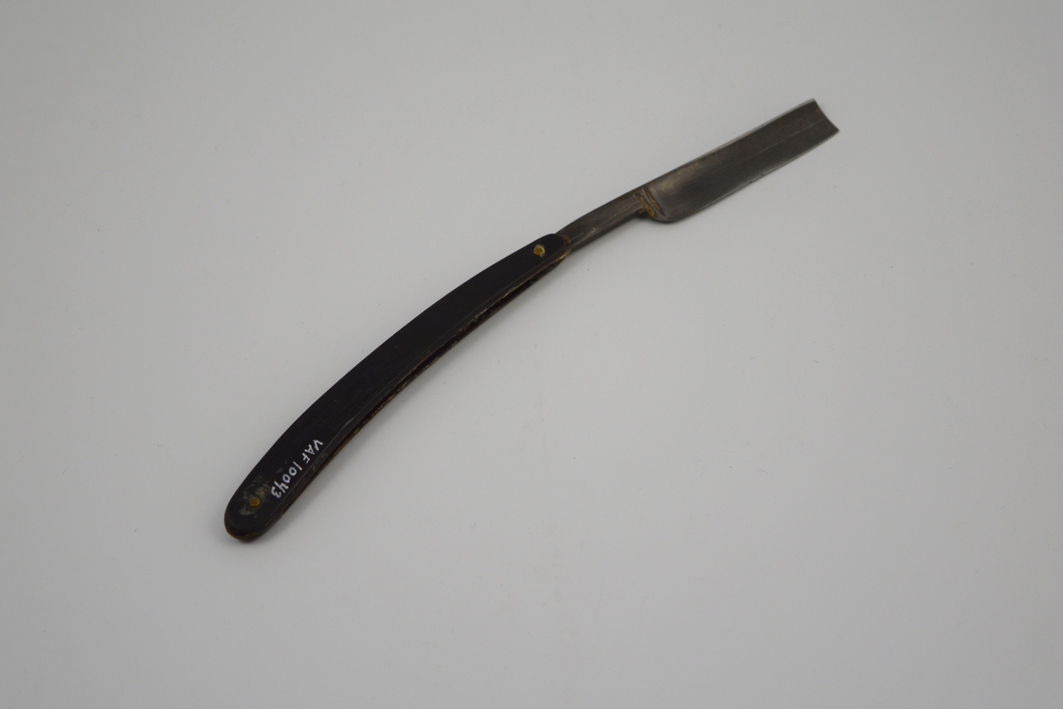 Sammenleggbar barberkniv med rett egg. Knivbladet har konisk tverrsnitt. Bladet munner ut i tynt skaft
med en krumning som holdegrep med fingeren. Skaftet er naglet fast til
kniven. Består av to deler som fungerer som beskyttelse i sammenlagt
stilling.