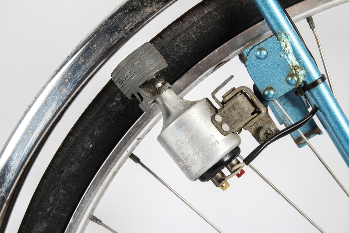 Blålakkert herresykkel med Torpedo trippel gir. Sykkelen har telleapparat ved fornav og avviserpinne bak. Dynamoen er plassert på bakhjul.