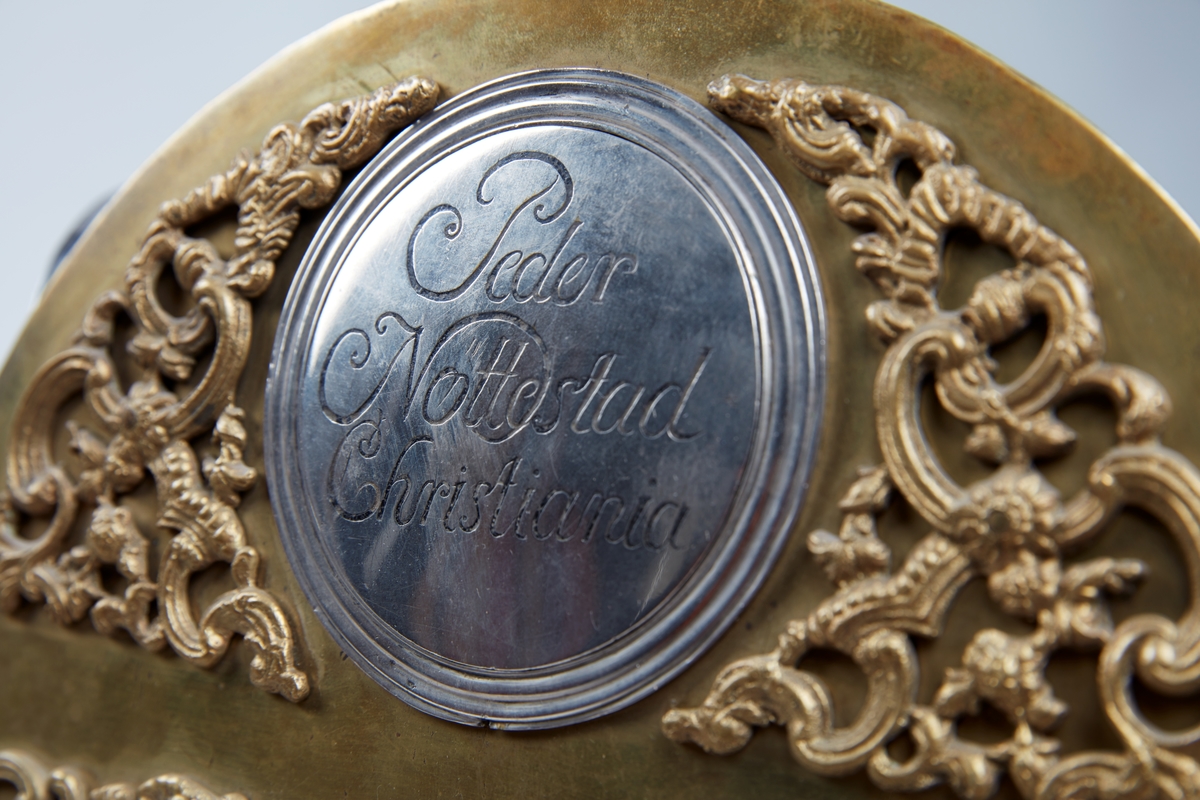 Rødmalt gulvur med forsiringer i form av nettverk, sped, stilisert akantus og rocaille. Urverket har sekund-, minutt- og datoviser og er forsynt med spillverk med to melodier.