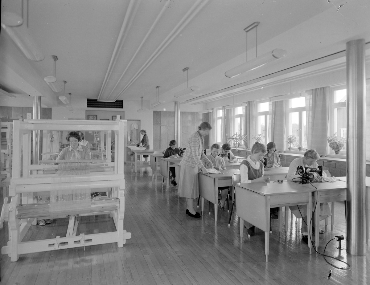 Norsk landbruks jubileumsutstilling 1959. En gruppe mennesker sitter i et rom med vever.