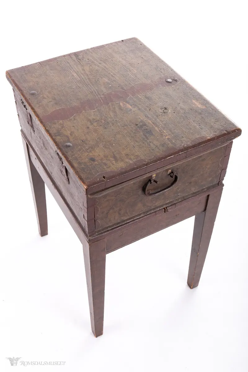 Ensfargede, bølgede dekorfelter midt på og på sidene av lokket, likeså rundt nøkkelhull og ved hjørnene.