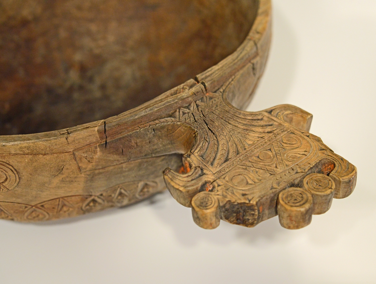 Oval øløse i tre med bredt skaft. Øløsen er dekorert med treutskjæringer i to border på korpus , samt utskjæringer på skaftet. Skaftet mangler en del av dekoren. Det er spor etter tidligere rødmaling.