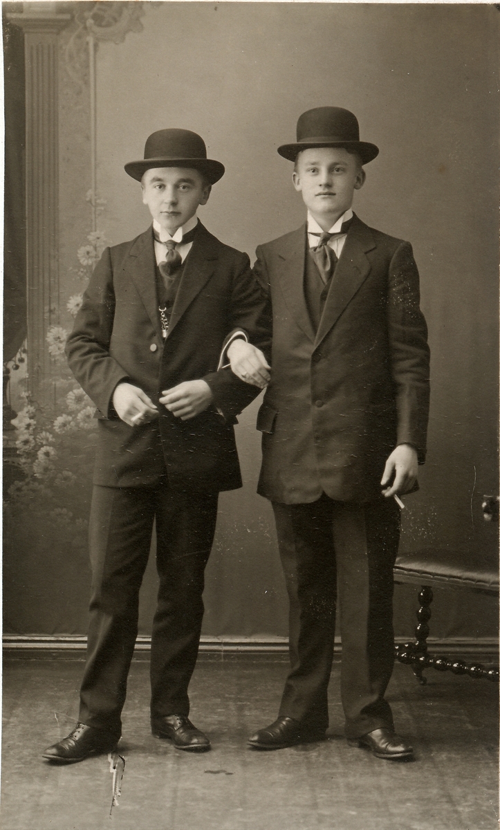 Portrett av to unge gutter kanskje mellom 13-15 år, med dress og bowlerhatt. Sigarett i hendene. Brødre?