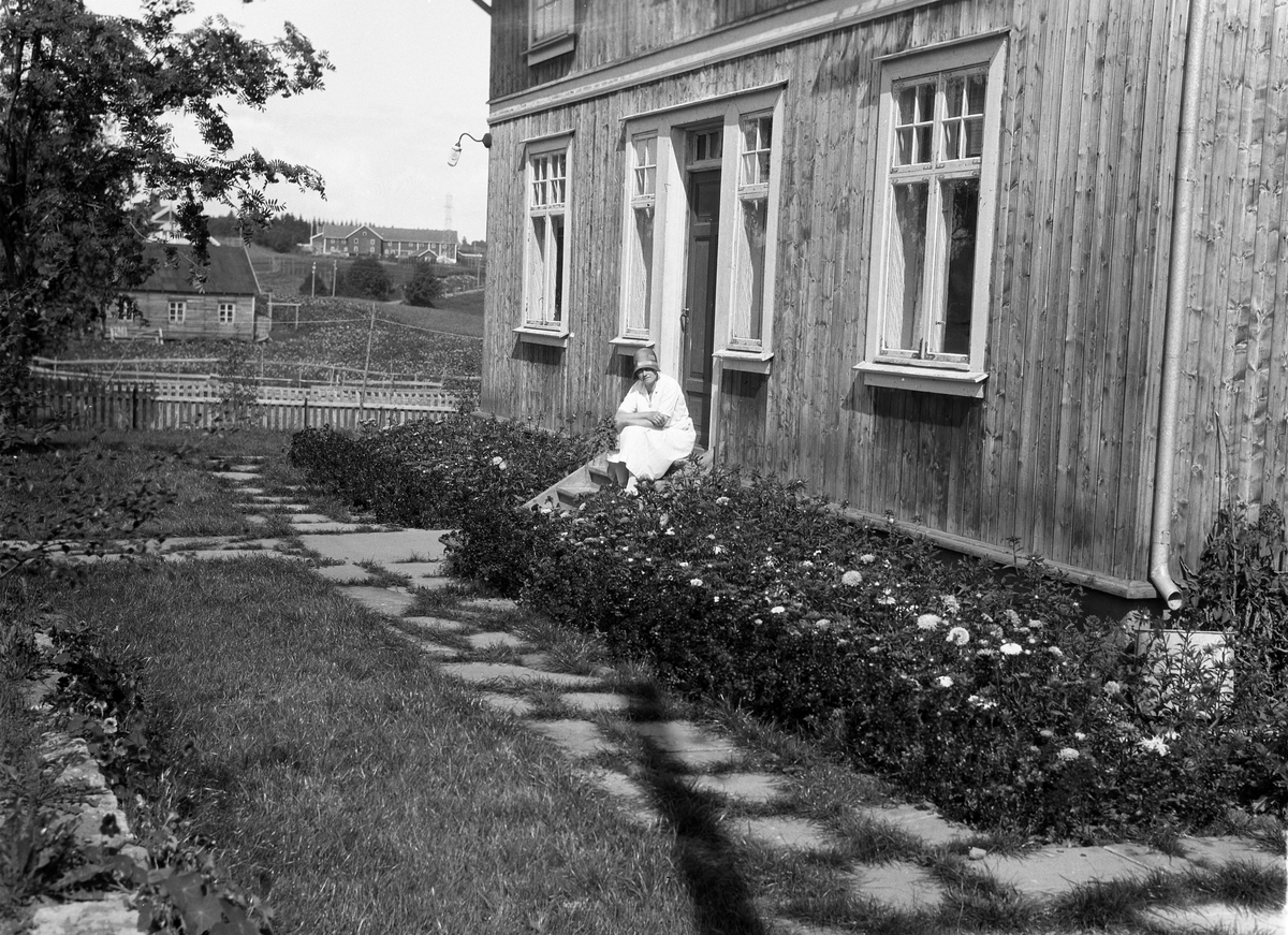 Antatt Karine Røisli som sitter på trappa til det som trolig er Rognhaug, Einar Solems eiendom, på Lena.