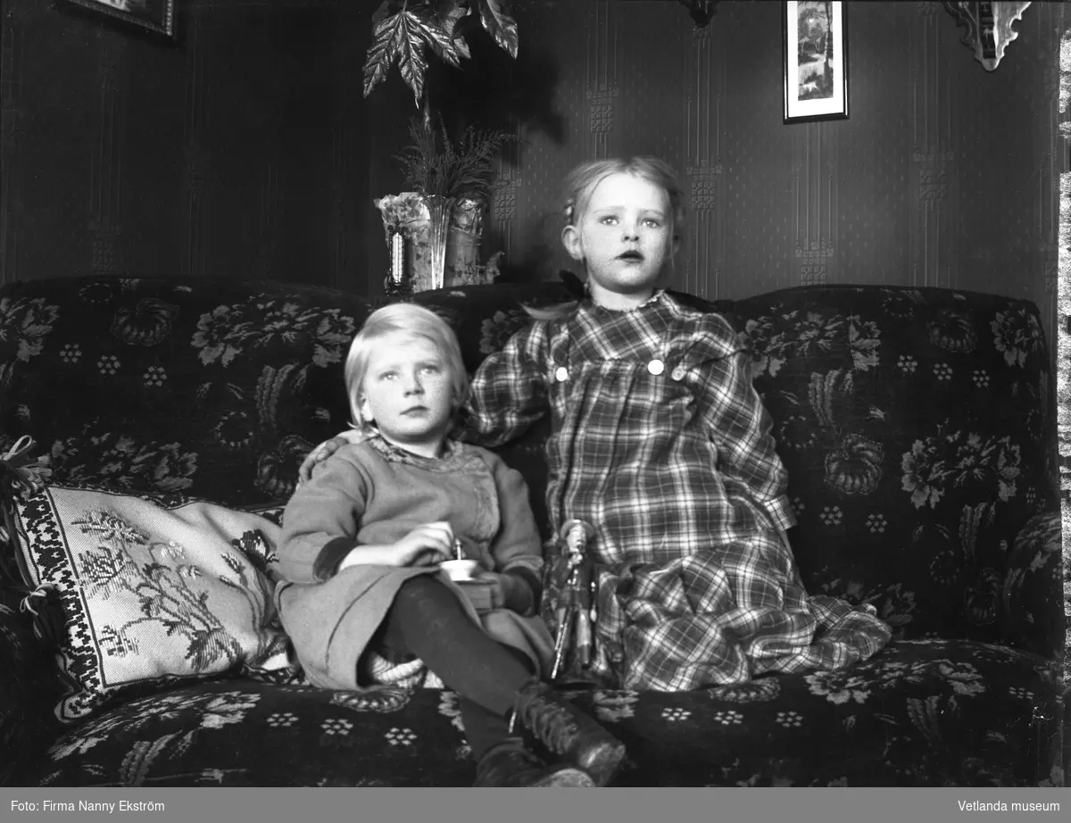 Interiör med två barn i en soffa.