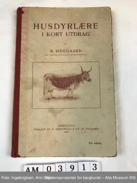 Bok med rød rygg og trykk på permene. På frontpermen er det et motiv av en ku av rasen fjordfe(?).